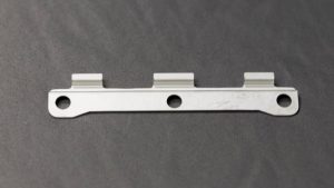 A flat cut blank beside a formed sheet metal part at Perry Tool & Die in Broomfield, Colorado