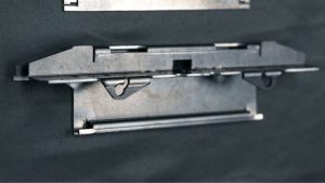 Formed sheet metal enclosure tray with a round cutout and mounting tabs, from Perry Tool & Die in Broomfield, Colorado